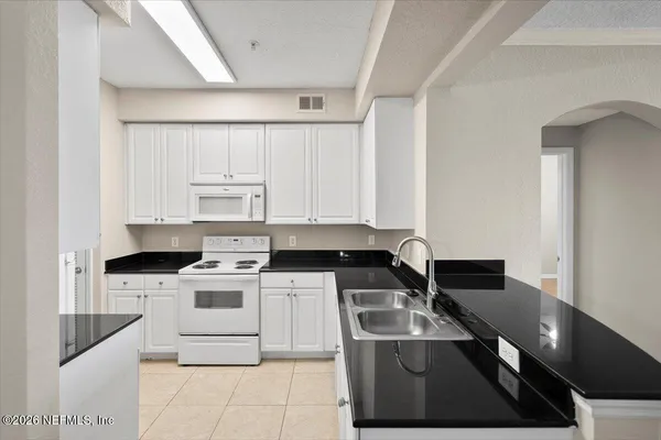 a kitchen with stainless steel appliances granite countertop a sink a stove and white cabinets