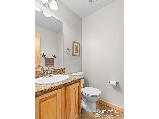 a bathroom with a granite countertop toilet sink and mirror