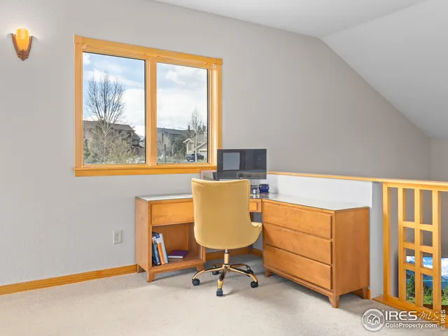 a view of a workspace with furniture and a window