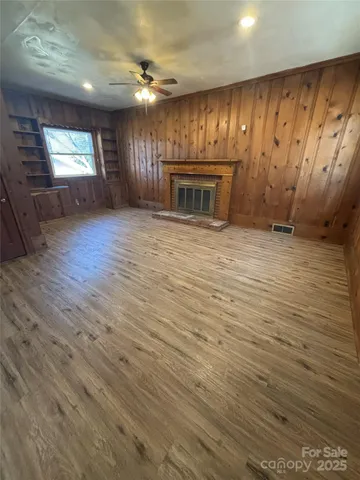 an empty room with wooden floor fireplace and windows