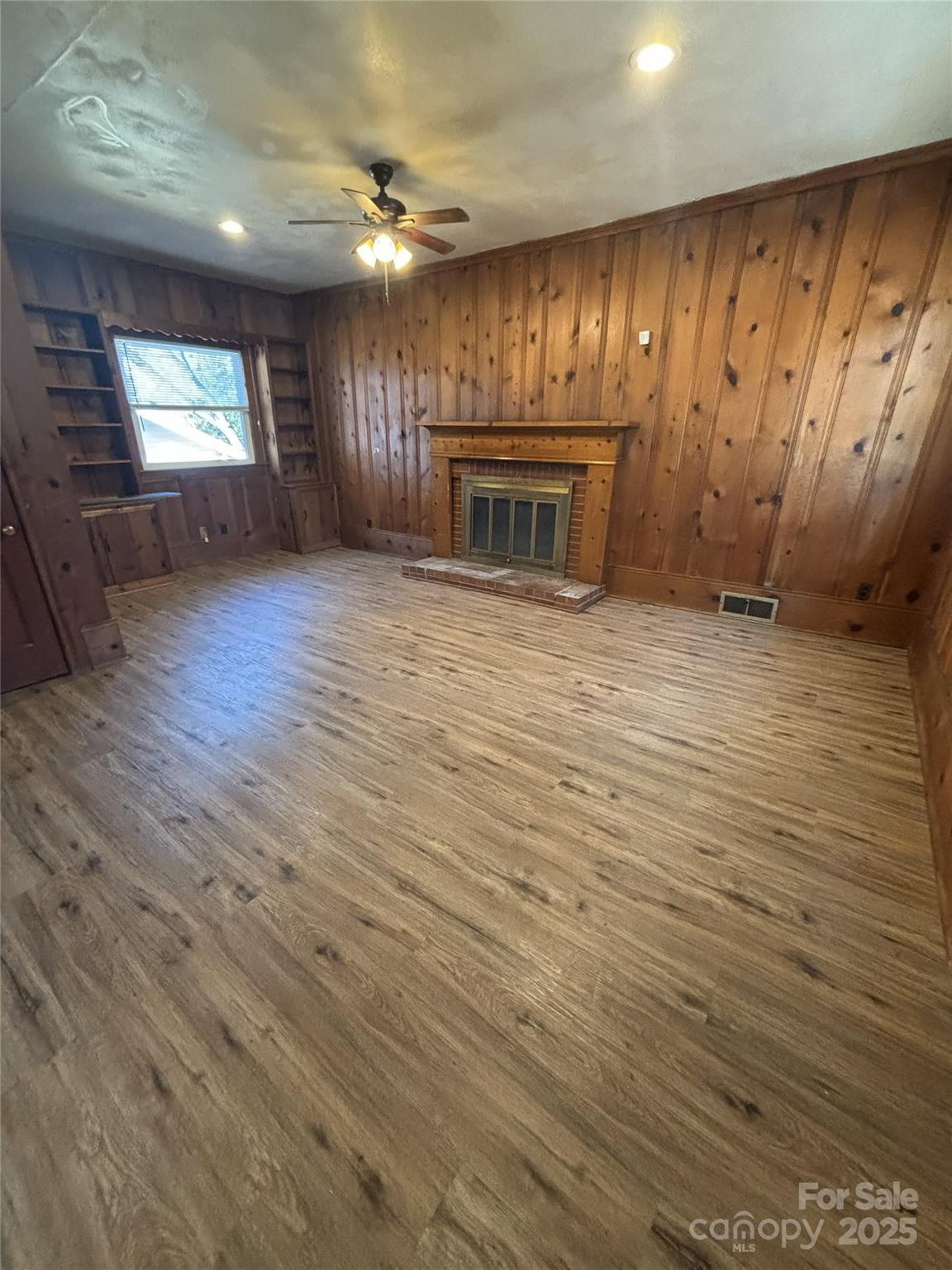 455 Spring Street Albemarle, NC 28001 - Photo 11 of 32 an empty room with wooden floor fireplace and windows