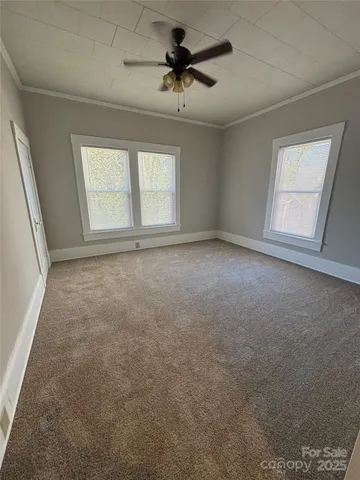 an empty room with windows and ceiling fan