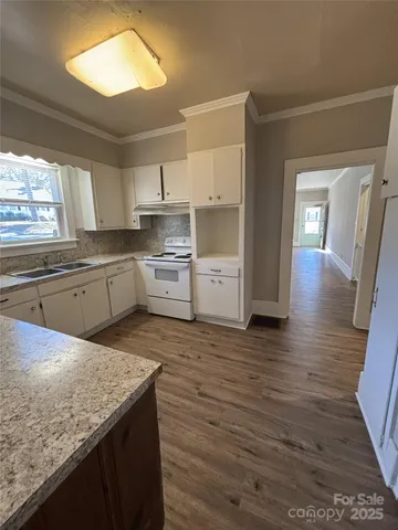 a kitchen with granite countertop a stove a sink and a refrigerator