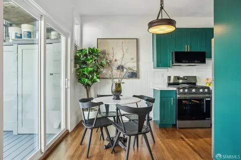 a kitchen with stainless steel appliances a stove a refrigerator and a dining table with wooden floor