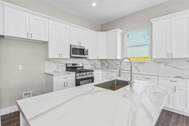 a kitchen with stainless steel appliances granite countertop a sink a stove top oven a granite counter tops and white cabinets