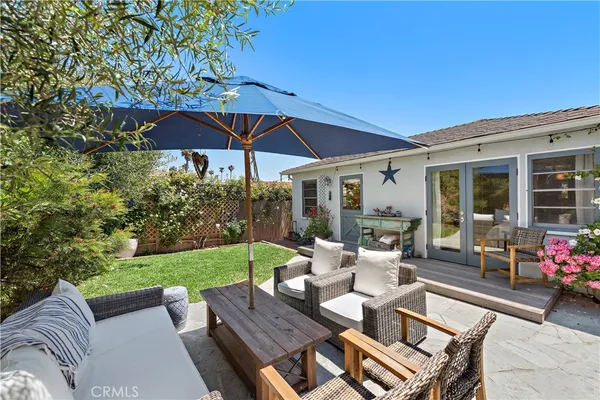 a view of a patio with couches table and chairs under an umbrella