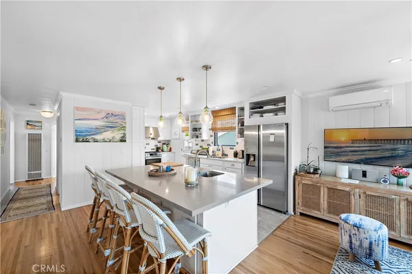 a dining hall with stainless steel appliances kitchen island granite countertop a table chairs and a refrigerator