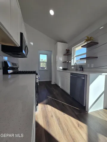 a kitchen with granite countertop white cabinets and black appliances