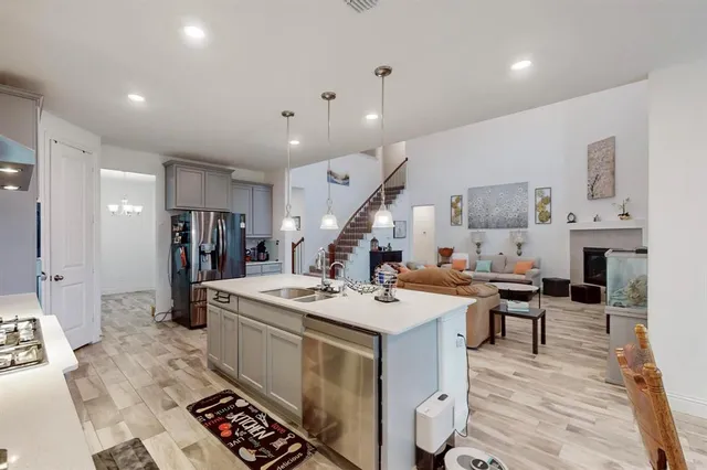 a open kitchen with stainless steel appliances granite countertop a sink dishwasher stove refrigerator and wooden floor