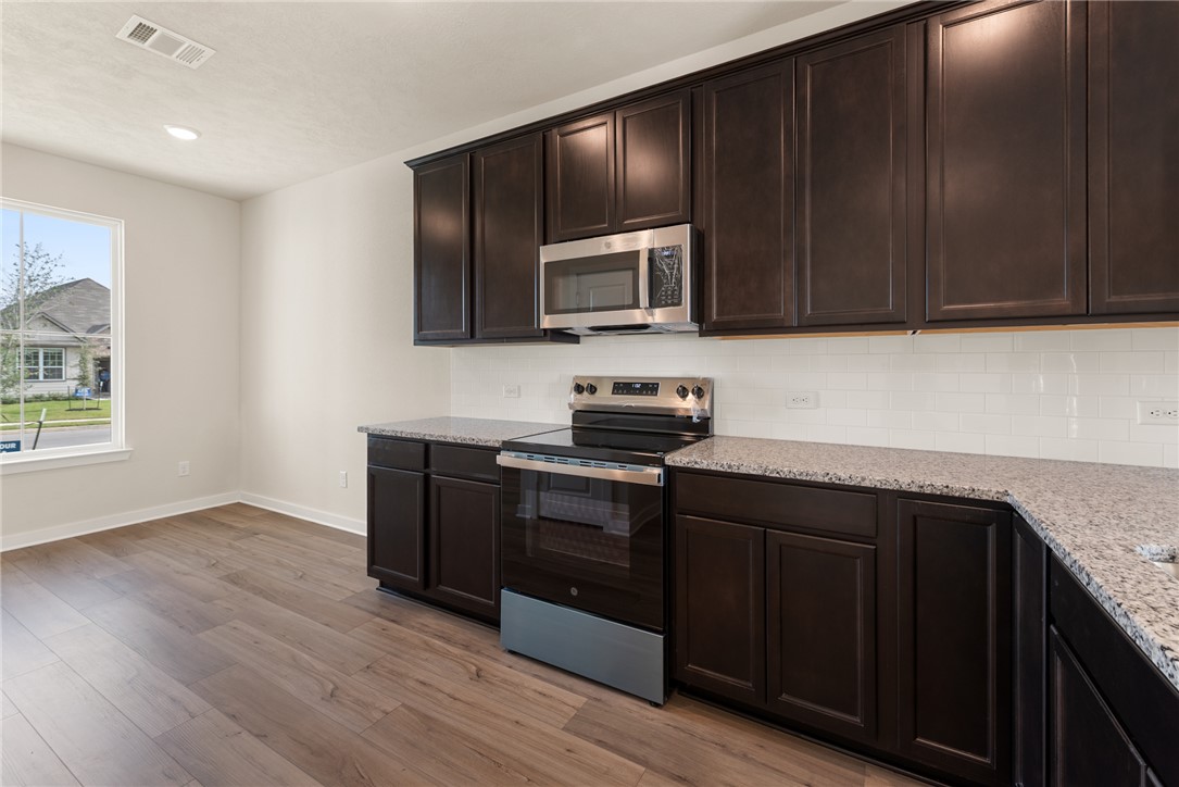 2427 Rooke Road Bryan, TX 77807 - Photo 14 of 38 a kitchen with wooden cabinets and black stainless steel appliances