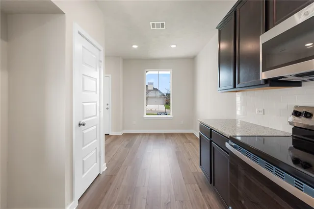 an empty room with wooden floor cabinets and windows