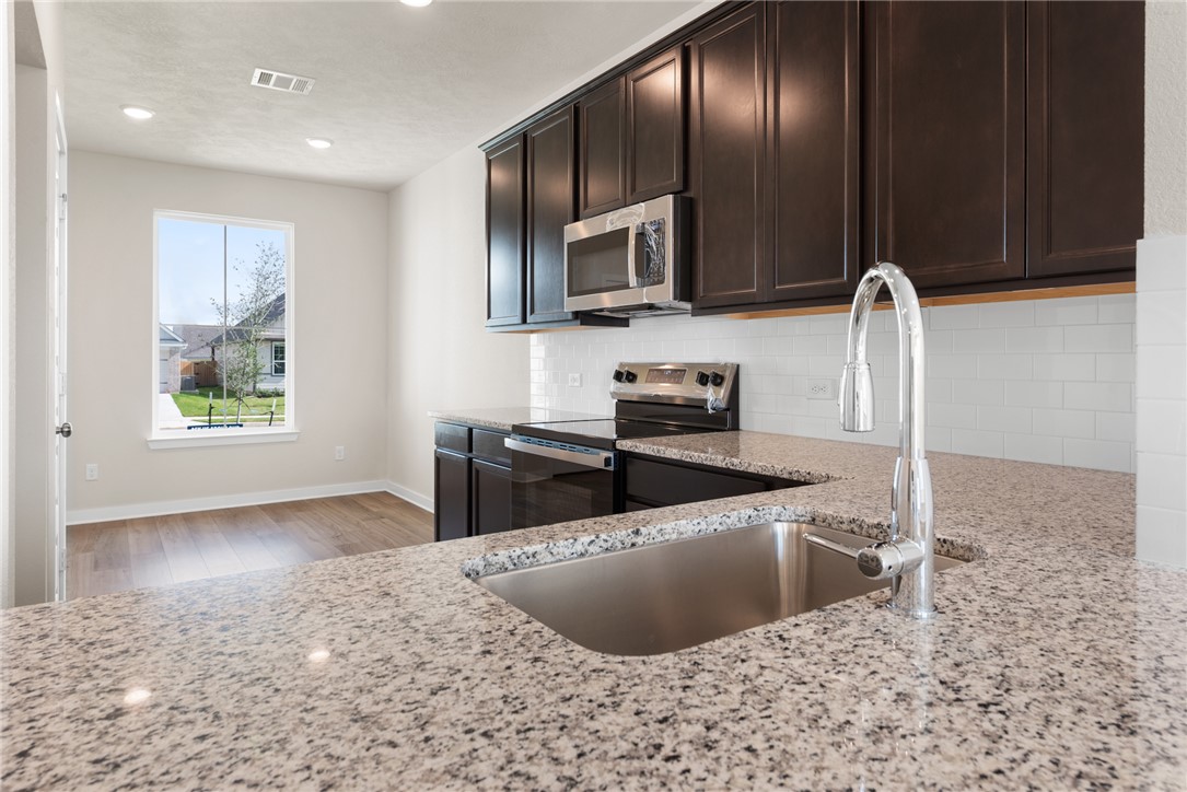 2427 Rooke Road Bryan, TX 77807 - Photo 16 of 38 a kitchen with stainless steel appliances granite countertop a sink a stove a microwave and cabinets