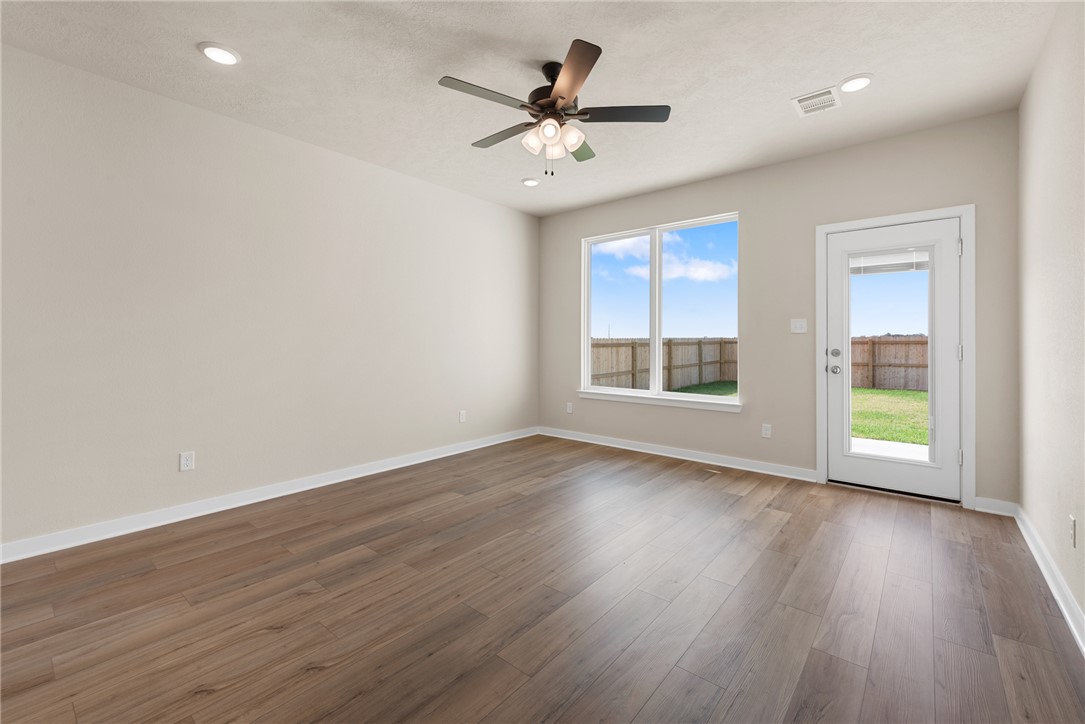 2427 Rooke Road Bryan, TX 77807 - Photo 18 of 38 an empty room with wooden floor chandelier fan and windows