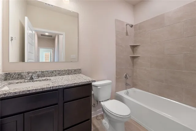 a bathroom with a granite countertop toilet a sink and a bathtub