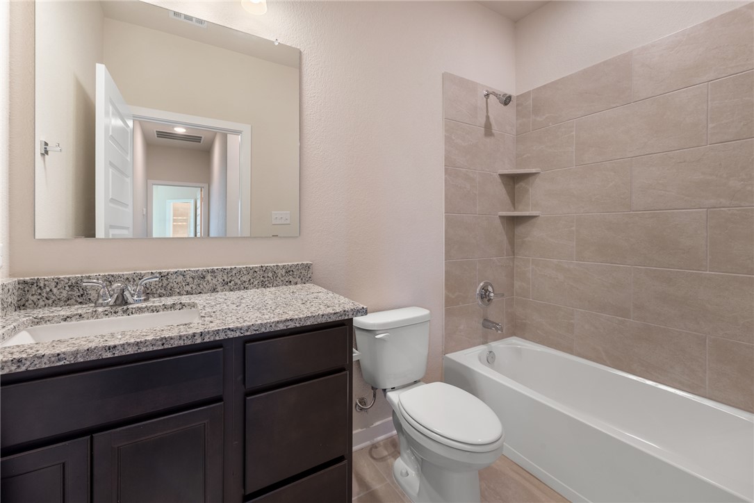 2427 Rooke Road Bryan, TX 77807 - Photo 25 of 38 a bathroom with a granite countertop toilet a sink and a bathtub
