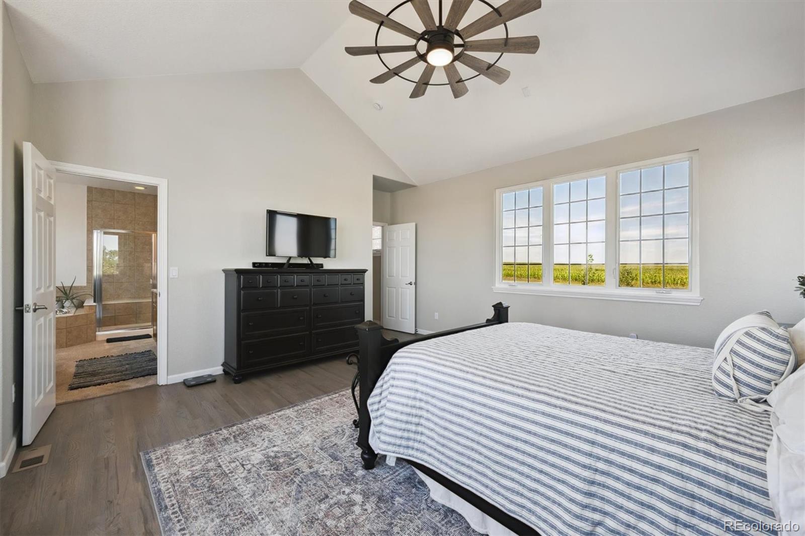 724 Imboden Road Watkins, CO 80137 - Photo 19 of 50 a bedroom with a bed a dresser and a chandelier