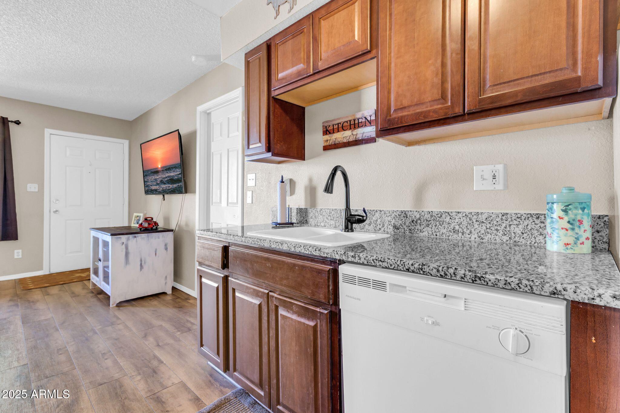 1440 North Idaho Road, Unit 2060 Apache Junction, AZ 85119 - Photo 10 of 24 a kitchen with stainless steel appliances granite countertop a sink dishwasher stove and cabinets with wooden floor