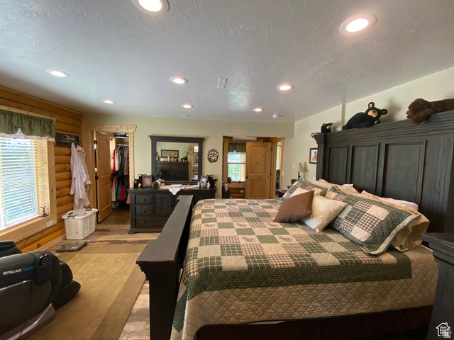 79 Auburn Forest Road Auburn, WY 83111 - Photo 28 of 76 Bedroom featuring log walls, a textured ceiling, recessed lighting, a walk in closet, and wood finished floors