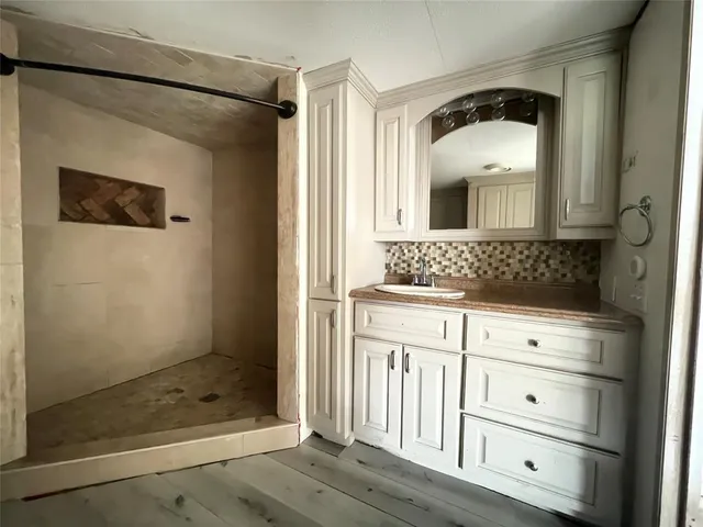 a bathroom with a granite countertop sink a mirror and shower