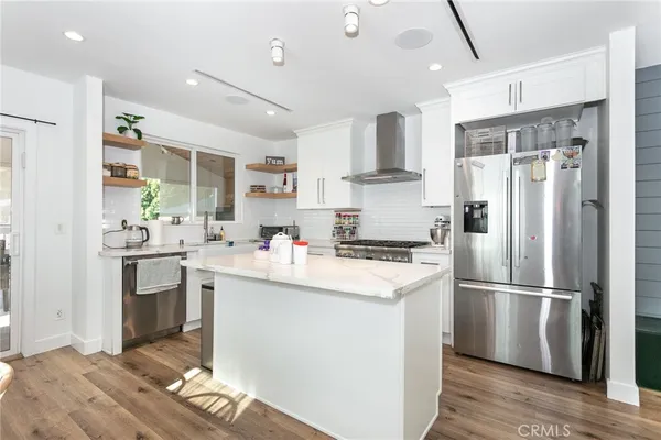 a kitchen with a refrigerator a sink dishwasher a stove and white cabinets with wooden floor