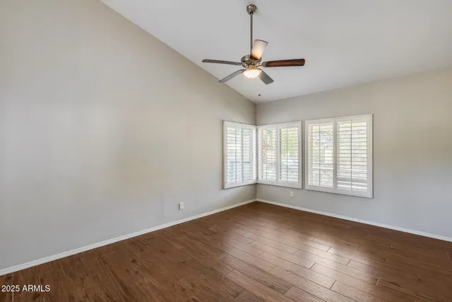 an empty room with wooden floor fireplace and windows