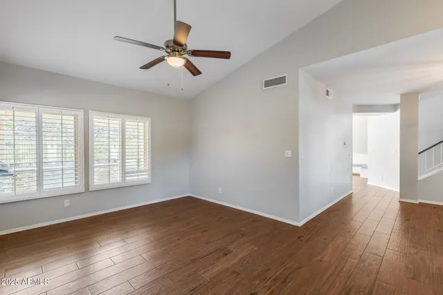 a view of an empty room with a window and wooden floor