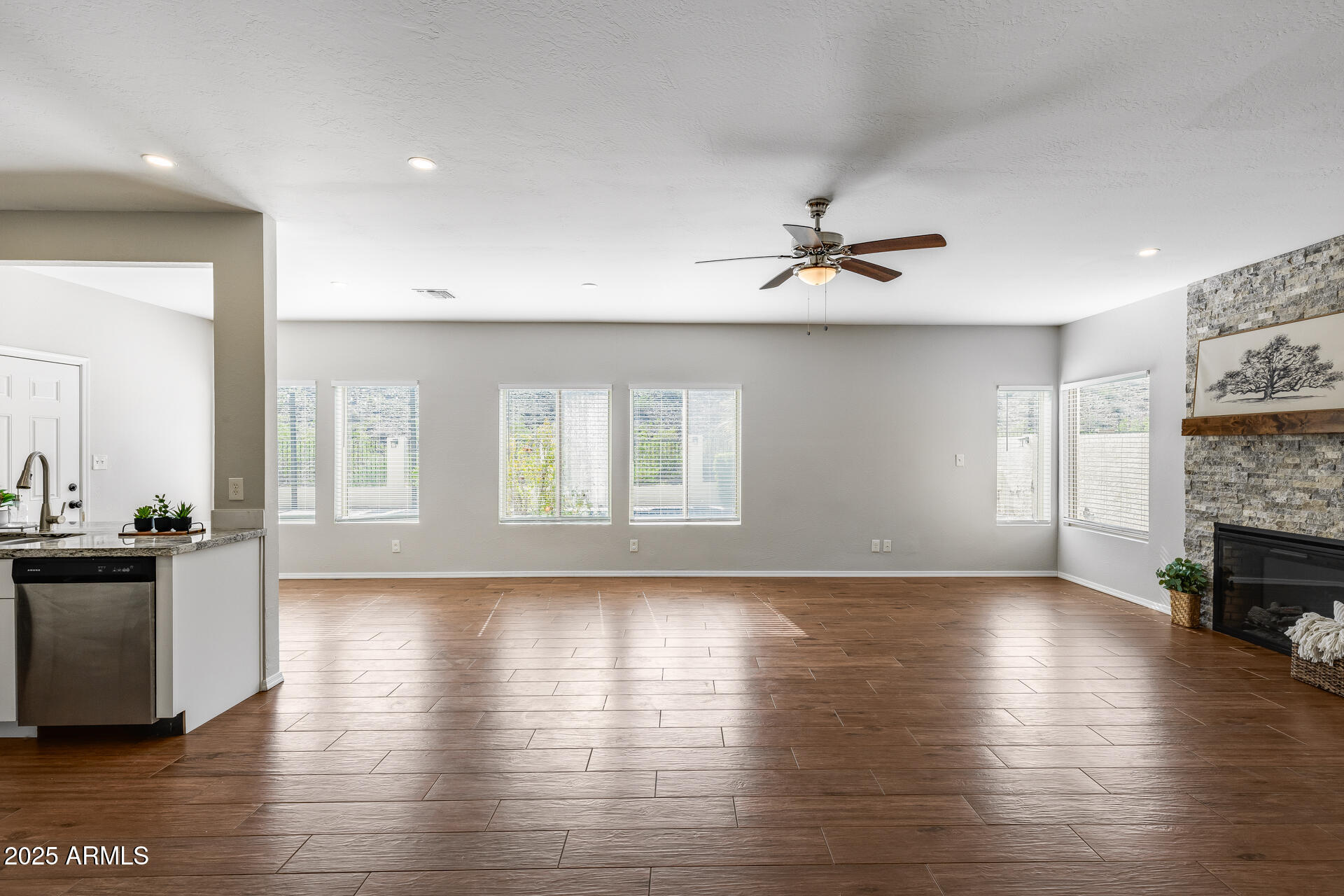 14452 South 40th Street Phoenix, AZ 85044 - Photo 25 of 92 an empty room with wooden floor a ceiling fan and a kitchen view