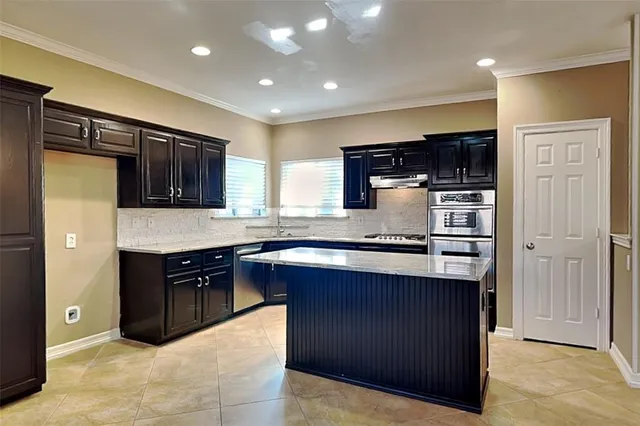 a kitchen with stainless steel appliances granite countertop wooden cabinets a stove top oven a sink and dishwasher