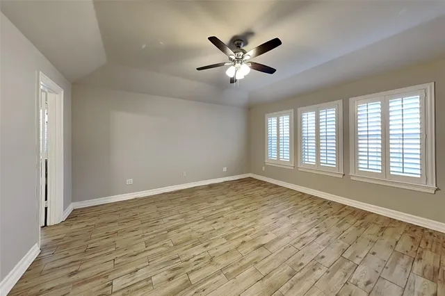 a view of an empty room with chandelier fan and a window