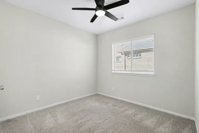 an empty room with a window and a fan