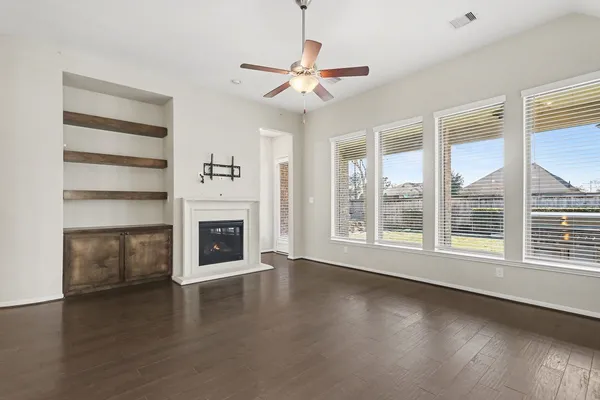 a view of a livingroom with a fireplace wooden floor and windows