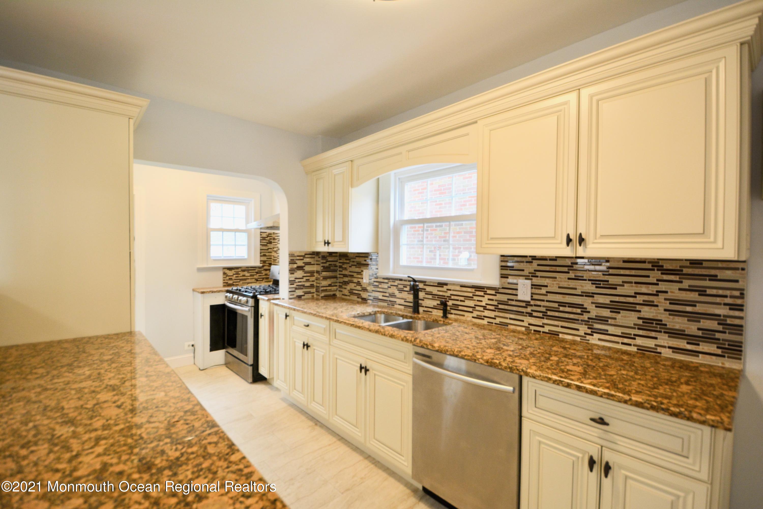 a kitchen with granite countertop a sink a stove cabinets and counter space