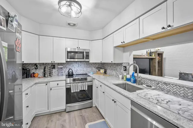 a kitchen with granite countertop a sink stainless steel appliances and white cabinets
