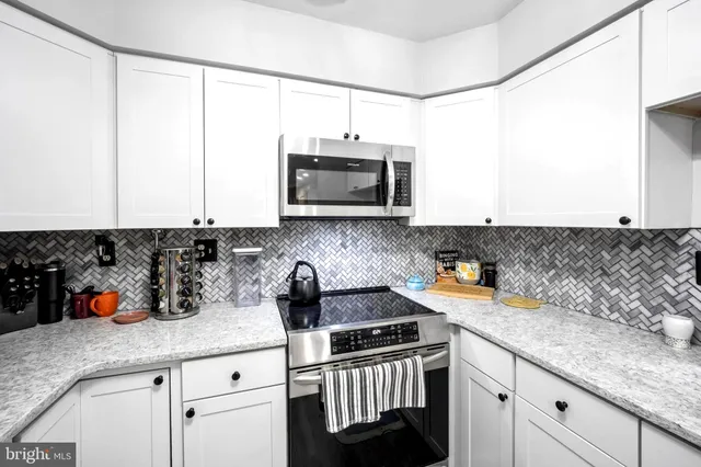 a kitchen with stainless steel appliances granite countertop a sink and a white cabinets