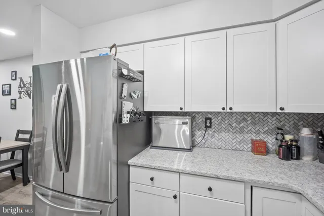 a kitchen with stainless steel appliances granite countertop a refrigerator a sink and white cabinets