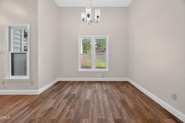 a view of an empty room with wooden floor and a ceiling fan
