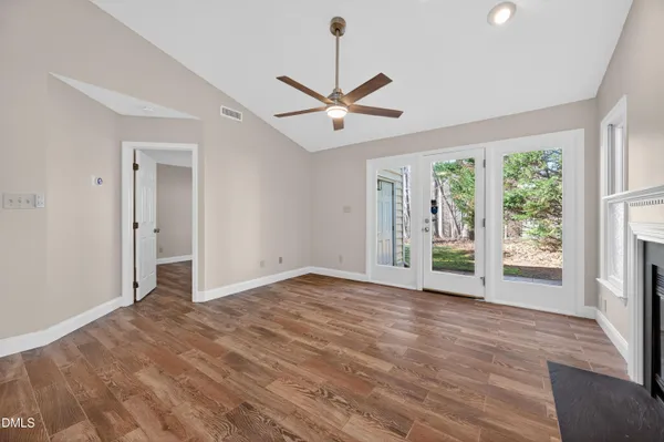 a view of an empty room with wooden floor fireplace and a window