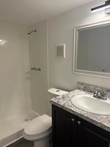 a bathroom with a granite countertop sink toilet and shower