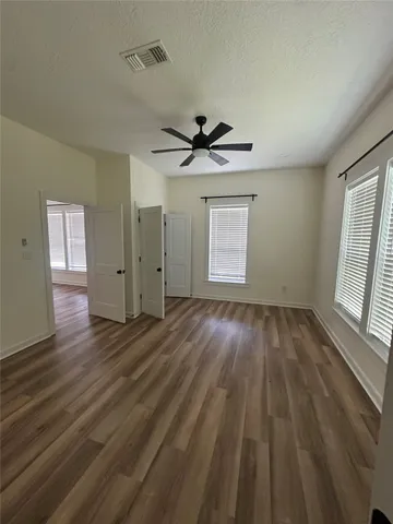 an empty room with wooden floor and windows