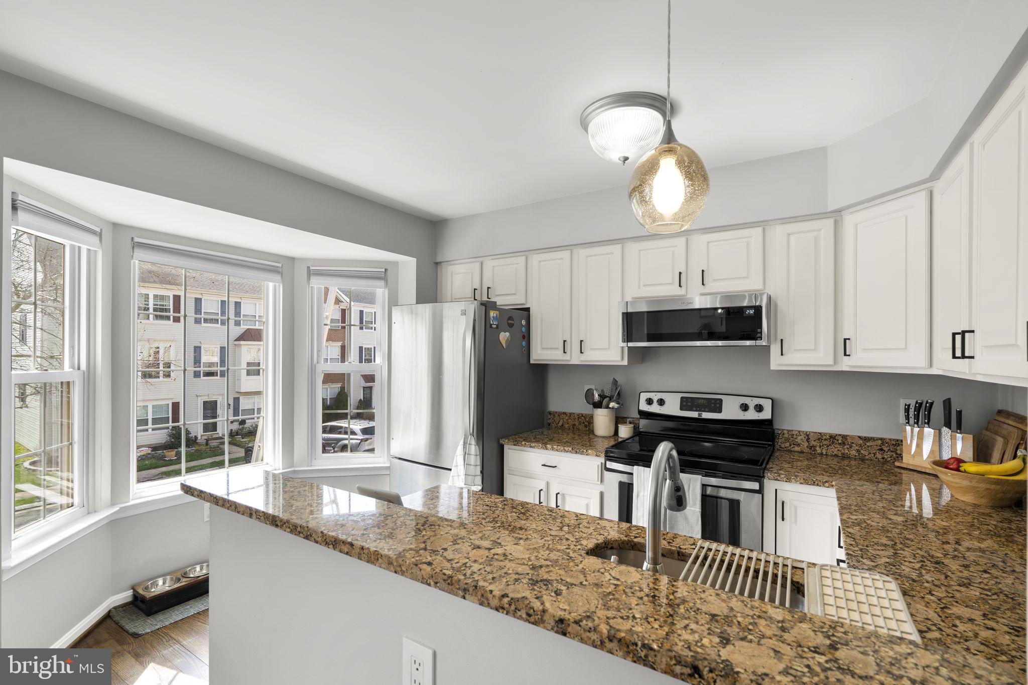 20250 Brookview Square Ashburn, VA 20147 - Photo 15 of 45 a kitchen with stainless steel appliances granite countertop a sink a stove a refrigerator cabinets and living room view