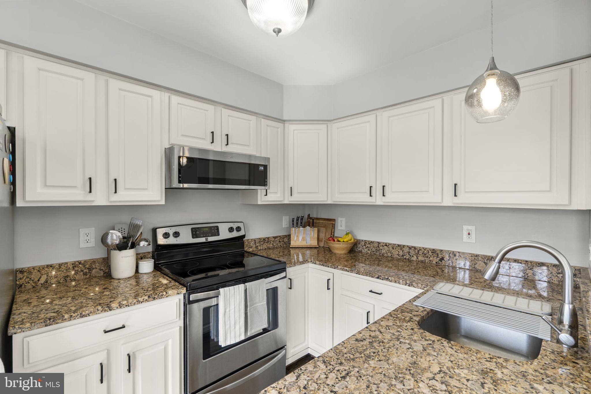 20250 Brookview Square Ashburn, VA 20147 - Photo 17 of 45 a kitchen with granite countertop a sink a stove a oven and white cabinets