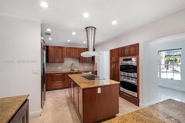 a kitchen with kitchen island granite countertop a stove and a sink