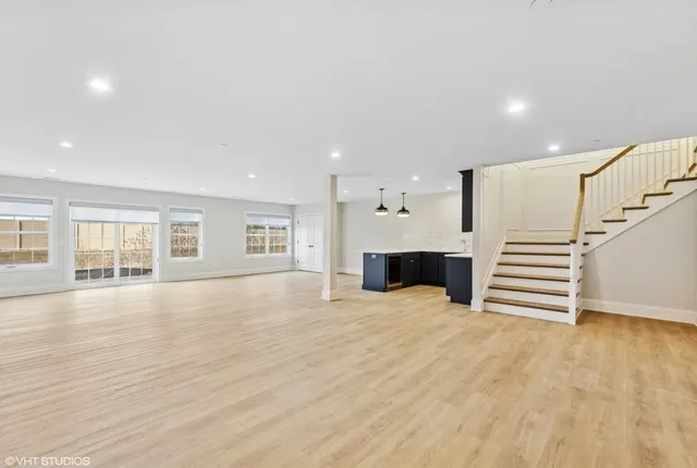 a view of an empty room with wooden floor and stairs