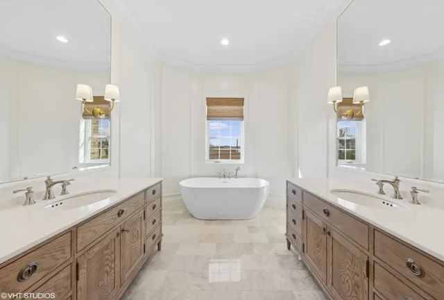 a bathroom with a double vanity sink mirror and bathtub