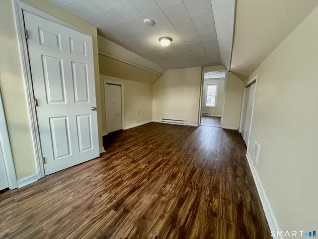 a view of empty room with window and wooden floor