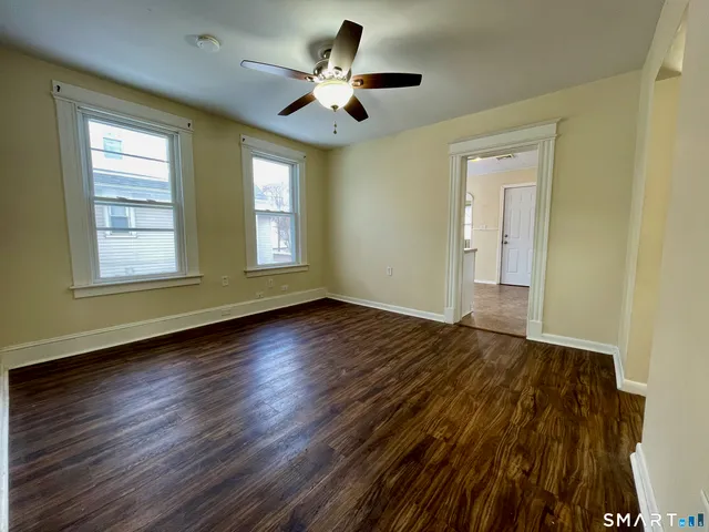 a view of empty room with wooden floor and fan
