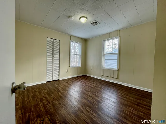 a view of an empty room with a window and wooden floor
