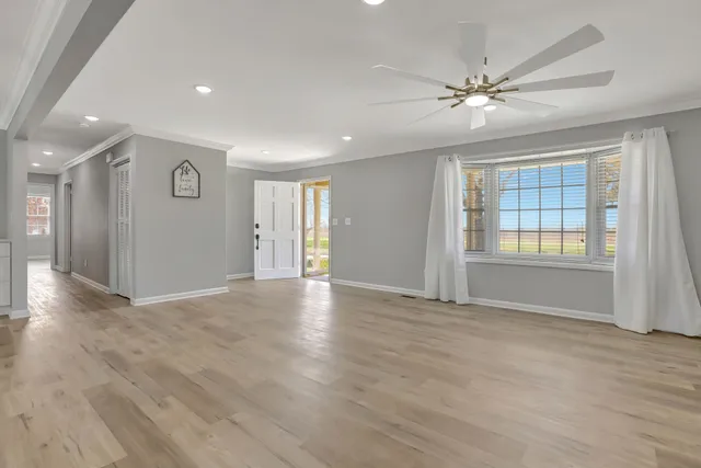 a view of an empty room with window and wooden floor