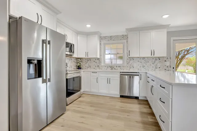 a kitchen with granite countertop white cabinets and white stainless steel appliances