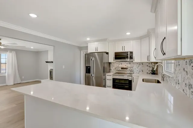 a kitchen with stainless steel appliances a stove a sink a microwave a refrigerator and cabinets